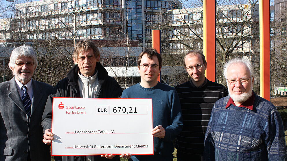 Foto (Universität Paderborn, Patrick Kleibold): Die Vertreter der Chemie freuen sich darüber, Uwe Hoffmann von der Paderborner Tafel einen Scheck in Höhe von 670,21 Euro überreichen zu können: (v.l.) Prof. Dr. Gerald Henkel, Uwe Hoffmann, Christian K