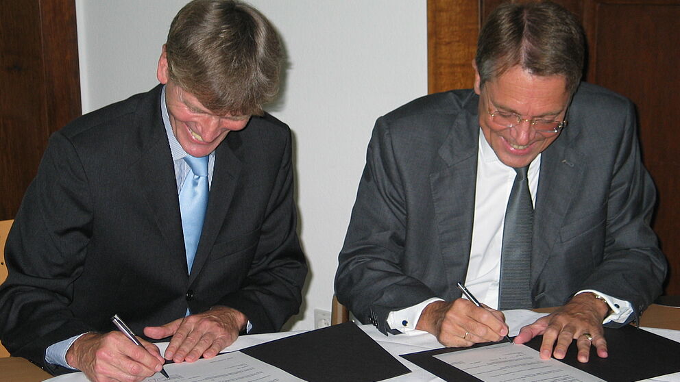 Foto (Ramona Wiesner): Die von Hella gestiftete Juniorprofessur für die Universität Paderborn wird vertraglich besiegelt durch Professor Dr. Nikolaus Risch (links) und Dr. Jürgen Behrend.