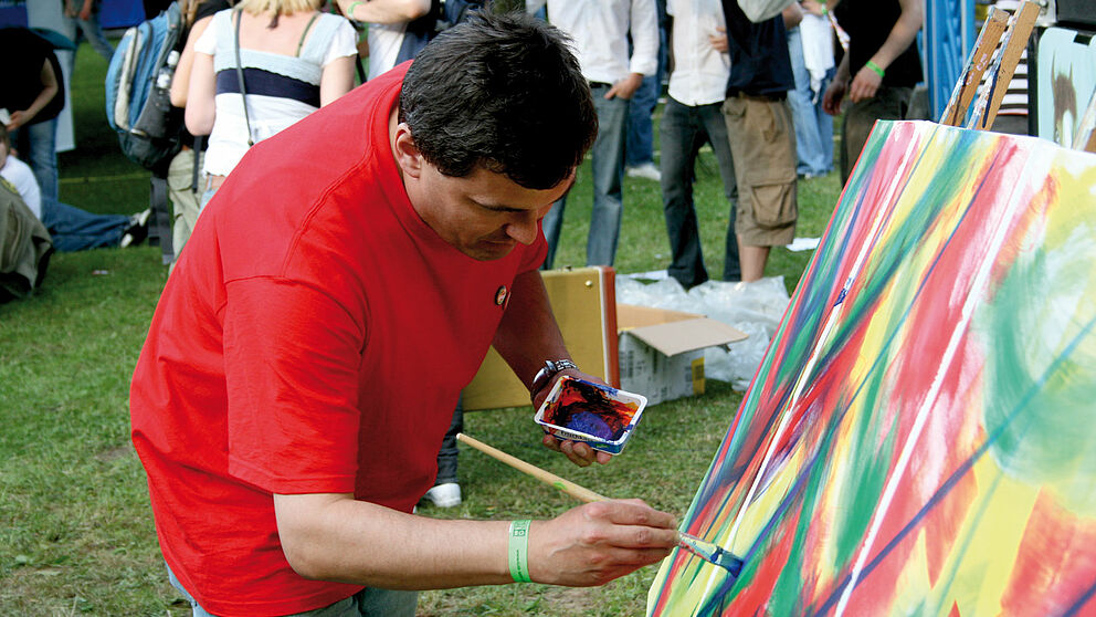 Foto (Universität Paderborn): Der Paderborner Künstler Bernward Schäfers malt das „Farbfestival“.