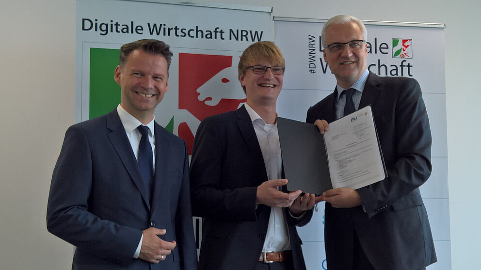Foto (Universität Paderborn, TecUP): Prof. Dr. Tobias Kollmann (l.) und NRW-Wirtschaftsminister Garrelt Duin (r.) überreichen Dr. Sebastian Vogt (m.), Geschäftsführer von TecUP, den offiziellen Förderbescheid.