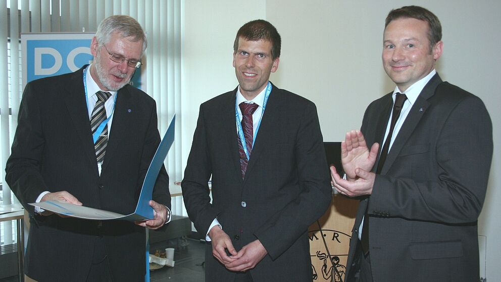 Foto (Deutsche Gesellschaft für Materialkunde DGM): Übergabe des Georg-Sachs-Preises der DGM an Dr.-Ing. Thomas Niendorf (Mitte) durch den Vorsitzenden der DGM Prof. Dr.-Ing. Hans-Jürgen Christ (links) und Prof. Dr. Alexander Hartmaier (rechts)
