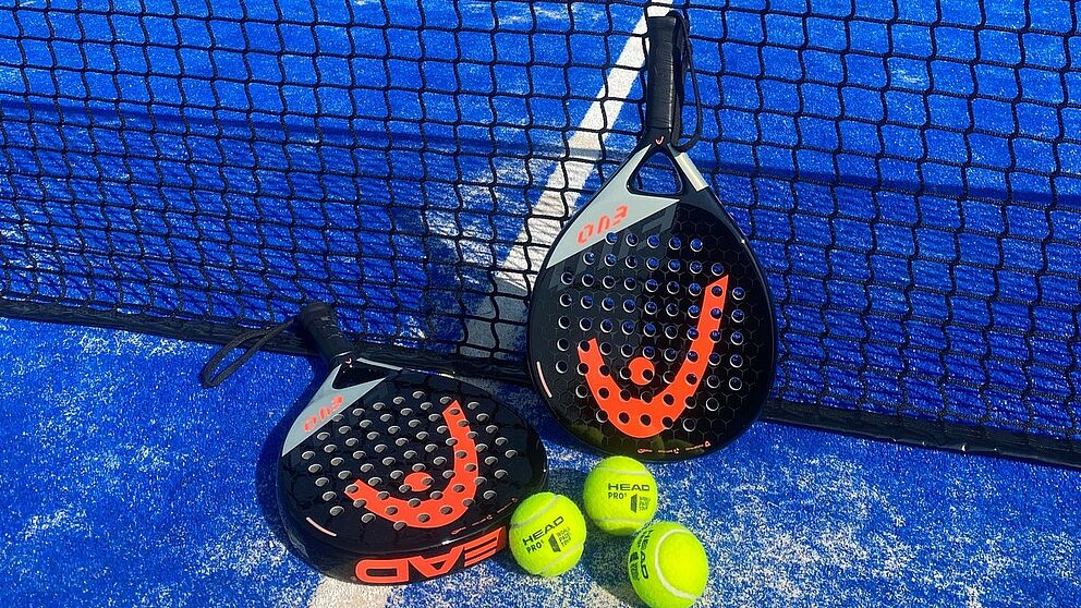 Padel rackets and balls leaning against the net on the padel facility on the sports campus of the Paderborn University.