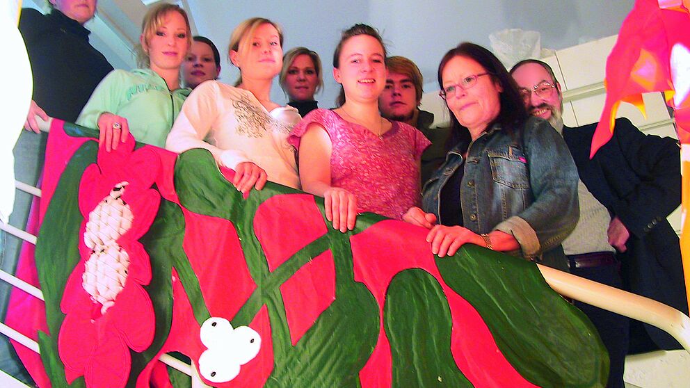 Foto: Treppe mit roter Fahne, von links: Anke Wester, Sarah Flüchter, Sonja Schröder, Eva Lammert, Maren Voigt, Christine Braun, Benedikt Breuer, Prof. Dorothea Reese-Heim, Museumsleiter Wulff E. Brebeck