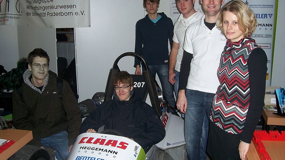 Foto (Mark Heinemann): Tobias Neufeld (li.) und der im Boliden sitzende Lukas Klein informierten sich bei Bastian Wolff (2. v. li., Marco Suthe, Sebastian Schriek und Dorothee Kaiser über Wirtschaftsingenieurwesen, Maschinenbau und Elektrotechnik.