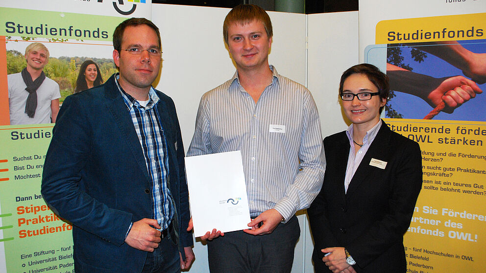 Foto (Stiftung Studienfonds OWL): v. li.: Dennis Kortebusch (Schatzmeister PHK), Stipendiat Sergii Mykhalskyi und Lena Steinhoff (Schriftführerin PHK) bei der feierlichen Stipendienvergabe im Audimax der Universität Paderborn. Nicht auf dem Foto: Stipen