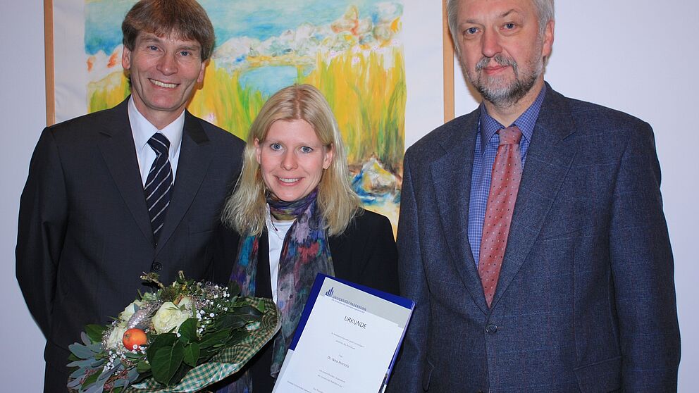 Foto (Universität Paderborn, Frauke Döll): Dr. Nina Hinrichs erhält von Präsident Prof. Dr. Nikolaus Risch und Prof. Dr. Wilhelm Schäfer, Vizepräsident für Forschung und wissenschaftlichen Nachwuchs, die Urkunde über das Stipendium.