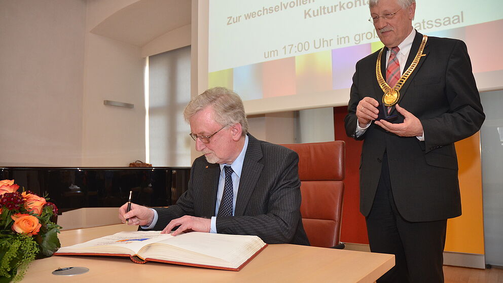 Foto (Stadt Paderborn): Prof. Dr. phil. Dr. h. c. mult. Peter Freese, Universität Paderborn, trägt sich in das Goldene Buch der Stadt Paderborn ein; rechts Bürgermeister Heinz Paus.