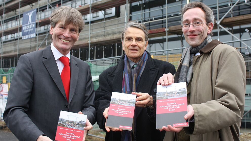 Foto (Universität Paderborn, Patrick Kleibold): Universitätspräsident Prof. Dr. Nikolaus Risch präsentiert mit den beiden Herausgebern Prof. Dr. Frank Göttmann und Dr. Thomas Reuther den Sammelband „Baustelle Informationsgesellschaft und Universit