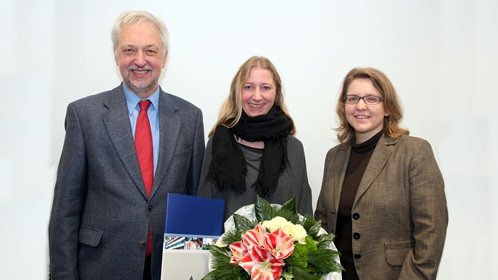Foto (Universität Paderborn, Nina Reckendorf): Uni-Präsident Prof. Dr. Wilhelm Schäfer und Prof. Dr. Christine Silberhorn (rechts), Vizepräsidentin für Forschung und wissenschaftlichen Nachwuchs, gratulieren Dr. Charis Goer (Mitte) zu dem Stipendium.