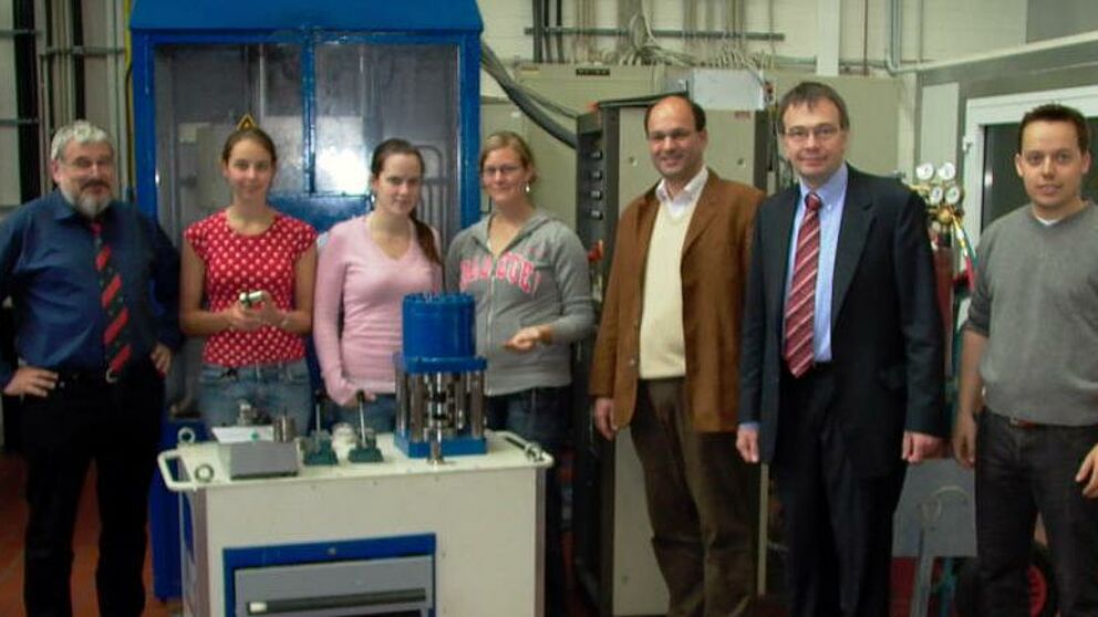 Foto (Universität Paderborn): Ulrich Lappe, Julia Lüttgenau, Luisa Puschmann, Ann-Katrin Ebert, Prof. Dr.-Ing. Ansgar Trächtler, Prof. Dr.-Ing. Werner Homberg und Daniel Hornjak vor einer Hydraulikpresse (v. li.)