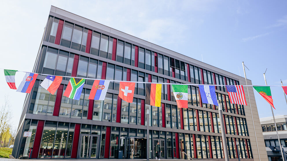 Verschiedene Länderflaggen vor einem Universitätsgebäude