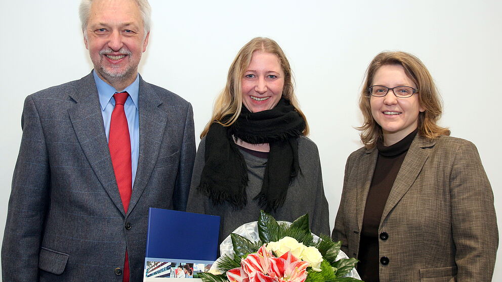 Foto (Universität Paderborn, Nina Reckendorf): Uni-Präsident Prof. Dr. Wilhelm Schäfer und Prof. Dr. Christine Silberhorn (rechts), Vizepräsidentin für Forschung und wissenschaftlichen Nachwuchs, gratulieren Dr. Charis Goer (Mitte) zu dem Stipendium.
