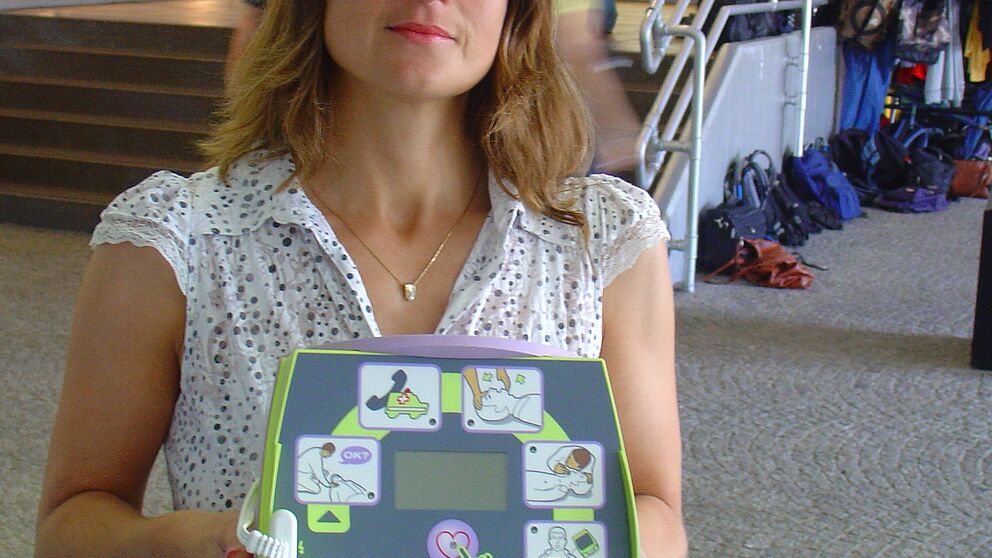 Foto (Tibor Werner Szolnoki): Diana Riedel hält einen Defibrillator in den Händen. Dieser ist mit einer Sprechfunktion sowie erklärenden Bildern ausgestattet und somit auch durch Laien nutzbar. Insgesamt sechs von diesen lebensrettenden Geräten gibt e