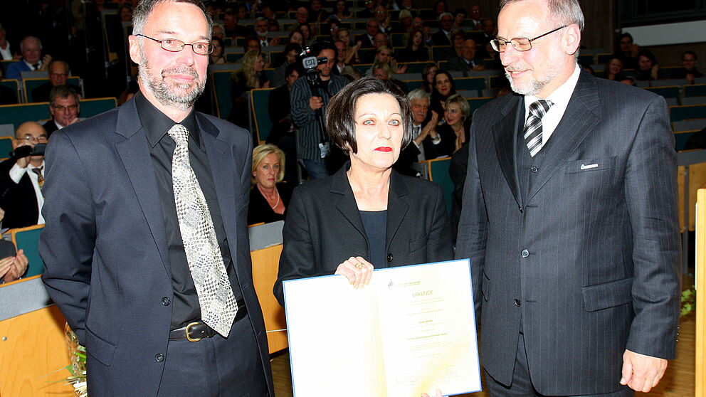 Foto (Universität Paderborn, Patrick Kleibold): Verleihung der Ehrendoktorwürde an die Literatur-Nobelpreisträgerin Herta Müller: Prof. Dr. Norbert Otto Eke (links) und Prof. Dr. Volker Peckhaus überreichen die Ehrenpromotion an Herta Müller.