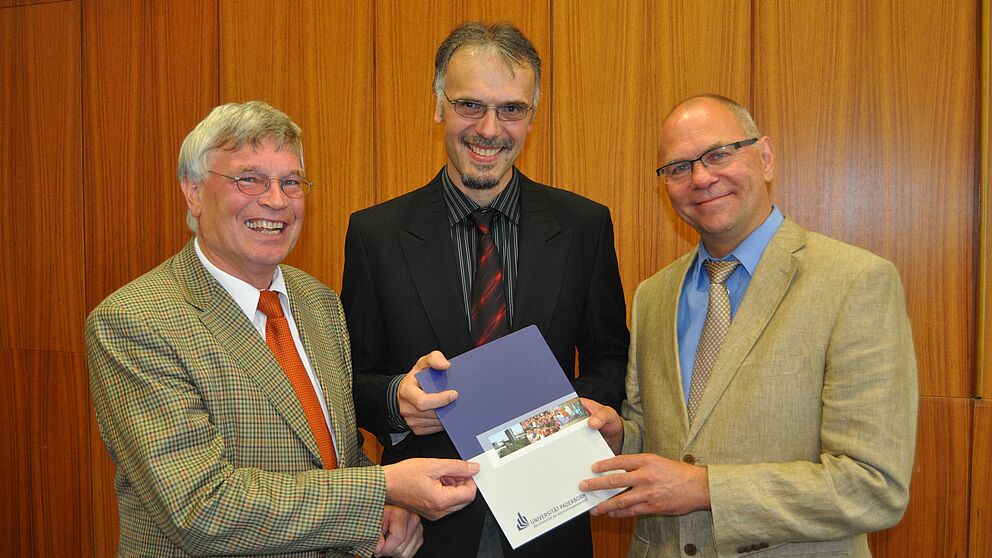 Foto (Mark Heinemann): Privatdozent Dr.-Ing. Gunter Kullmer (Mitte) erhält die Professorenurkunde aus den Händen des Dekans der Fakultät für Maschinenbau, Prof. Dr.-Ing. Detmar Zimmer (rechts), und Prof. Dr.-Ing. Hans Albert Richard (links).