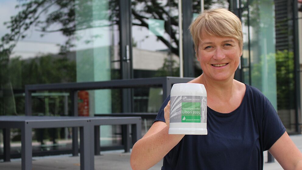Foto: (Universität Paderborn, Julia Pieper) Ein Krug extra für Libori: Alexandra Dickhoff von Alumni Paderborn lädt ein zum Ehemaligen-Treff am Libori-Freitag. Die ersten 50 Besucher erhalten den aktuellen Alumni-Krug.