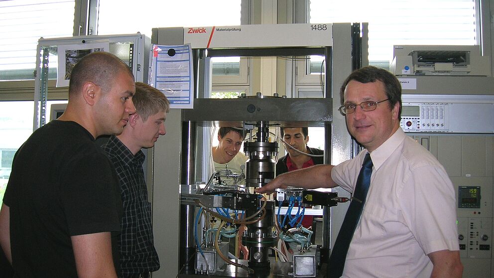 Foto (Julius Kolossa): Prof.-Dr. Ing. Hans Jürgen Maier (rechts) diskutiert mit (v. l.) Dr. Demircan Canadinc, Dipl.-Ing. Sergej Tschumak, Dipl.-Ing. Stefan Wilmanns und Dipl.-Ing. Ismail Caylak das Prinzip der Werkstoffprüfung bei hohen Temperaturen.