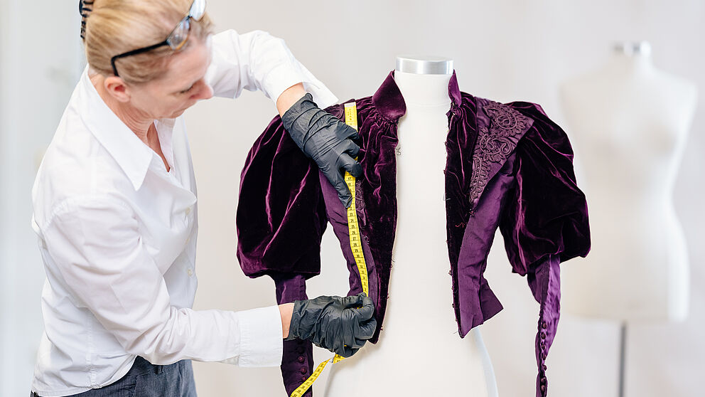 Foto (Universität Paderborn, Besim Mazhiqi): Prof. Dr. Kerstin Kraft von der Universität Paderborn untersucht historische Kleidungsstücke, um daraus Rückschlüsse auf frühere Bewegungsformen zu ziehen.