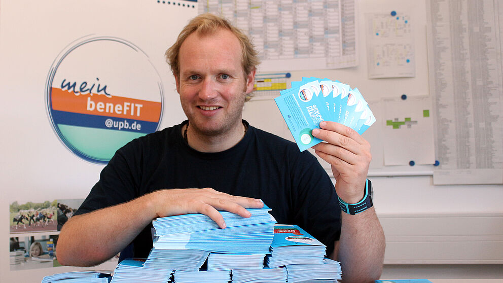 Foto (Universität Paderborn, Heiko Appelbaum): Frisch gedruckt: Dennis Fergland präsentiert die neuen Gesundheitspässe.