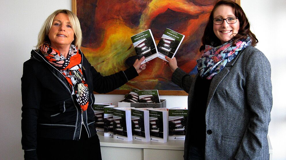 Foto (Universität Paderborn, Cornelia Filter): Birgitt Lammert (links), externe Koordinatorin des Studiums für Ältere, und Katharina Braun, studentische Hilfskraft im Sekretariat, mit den druckfrischen Studienführern.