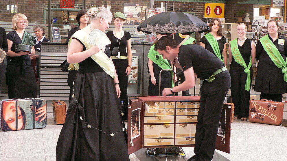 Foto: Bahnhof Weimar, Performance von Sonja Böhlen als Herzogin Anna Amalia und Mirko Winter als Kavalier zu einem Museumskoffer