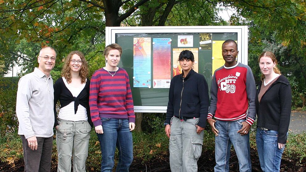 Foto (v. li.): Vor dem neuen Schaukasten: Studierendenpfarrer Matthias Surall, Studentin Katrin Annegarn, Gemeindeassistentin Alessandra Steinbrucker, Küsterin Elisabeth Jansen, Gemeindeassistent Francis Gnebehi und Verwaltungsfachangestellte Jennifer Ge