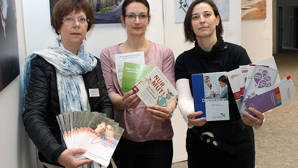 Foto (Universität Paderborn, Heiko Appelbaum): Hildegard Harmeier, Sandra Bischof und Dr. Yvonne Koch (v. l.) werben vor einer Bilderausstellung für einen offensiven Umgang mit der Depression.