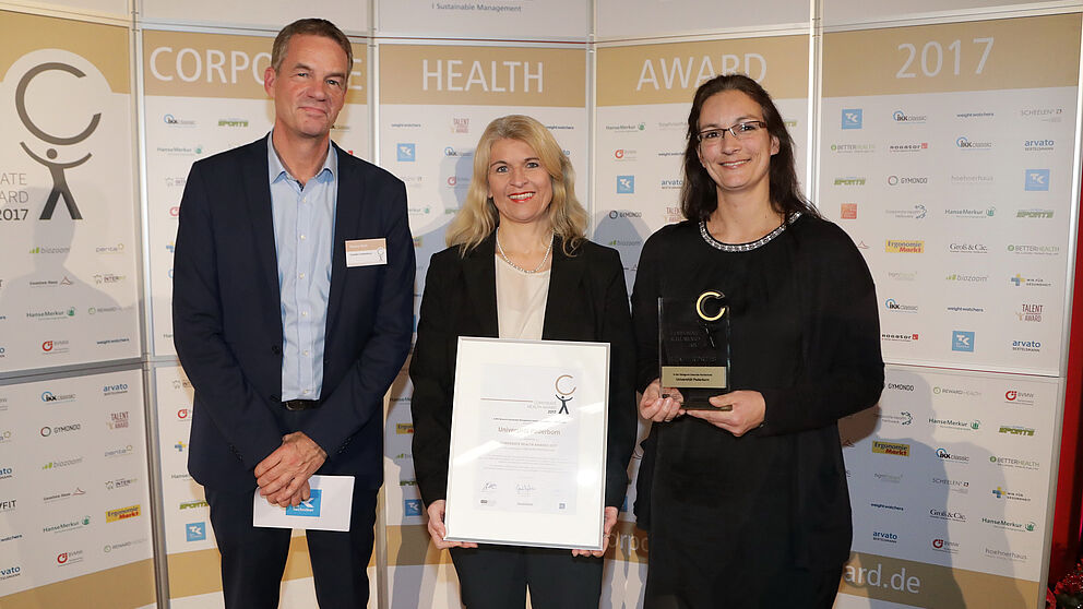 Foto (EuPD Research Sustainable Management GmbH): (v. l.) Thomas Holm, Leiter des Gesundheitsmanagements bei der Techniker Krankenkasse, überreichte den Preis an Diana Riedel und Sandra Bischof.