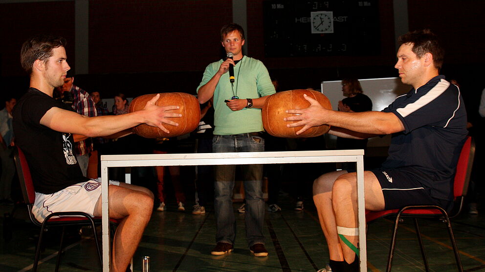 Foto (Universität Paderborn, Patrick Kleibold): Wer kann einen Medizinball mit ausgestreckten Armen länger halten? Uli Kussin und Martin Busch lieferten ein packendes Duell.