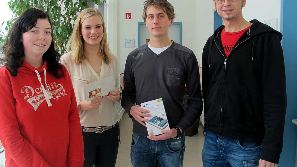 Foto (Universität Paderborn, Cinderella Schröder): Jörn Sickelmann (rechts) bei der Übergabe der Sachpreise. Die glücklichen Gewinner/innen (v. re.): Jens Beutel, Alina Jonas und Janine Hamm.