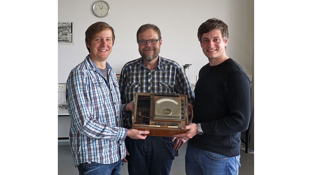 Foto (Heike Probst) (v. l. n. r.): Dr. Marc Sacher und Wilfried Bröckling (beide Uni Paderborn) und Tim Müller, Physik-Lehrer am Reismann-Gymnasium, freuen sich über die Übergabe des historischen Messgeräts und die geplante Kooperation im Rahmen der 