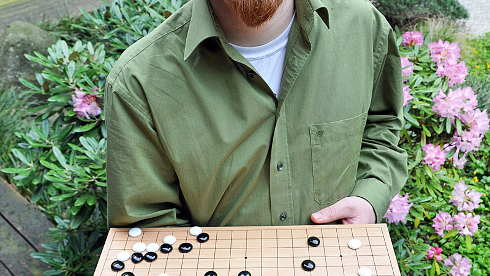 Foto (Katharina Bätz): Lars Schäfers zeigt eine Spielsituation auf einem Go-Brett.