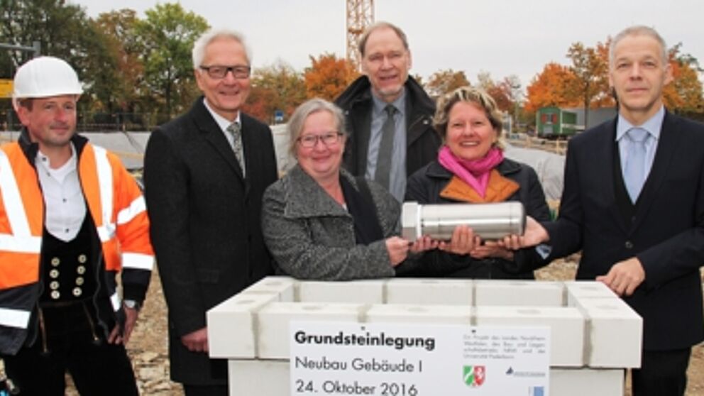 Foto (Universität Paderborn, Vanessa Dreibrodt): (v. l.) Gemeinsam mit Polier Mathias Bust versenkten Martin Pantke, stellv. Bürgermeister Stadt Paderborn, Simone Probst, Vizepräsidentin der Universität Paderborn, Rolf Holler, Niederlassungsleiter des