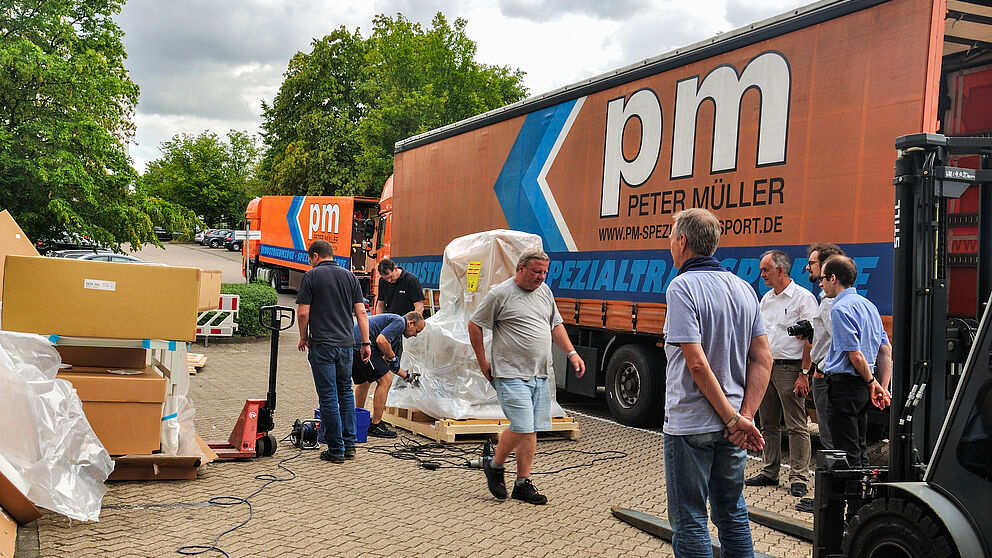 Foto (Department Physik): Das neue Transmissionselektronenmikroskop des Departments Physik wird angeliefert. Die Physiker beobachten gespannt, wie die Erste von neun Kisten ausgepackt wird.