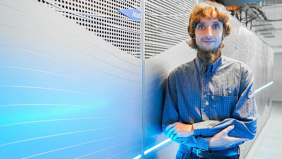 Prof. Dr. Martin Brehm, Heisenberg Professor at Paderborn University, stands in front of the Noctua 2 supercomputer.