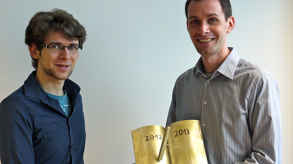 Foto (Universität Paderborn, Heike Probst): Prof. Dr. Thomas Zentgraf (rechts) freut sich mit Philip Heringlake über die „Goldene Kreide“ für die beste Lehrveranstaltung.