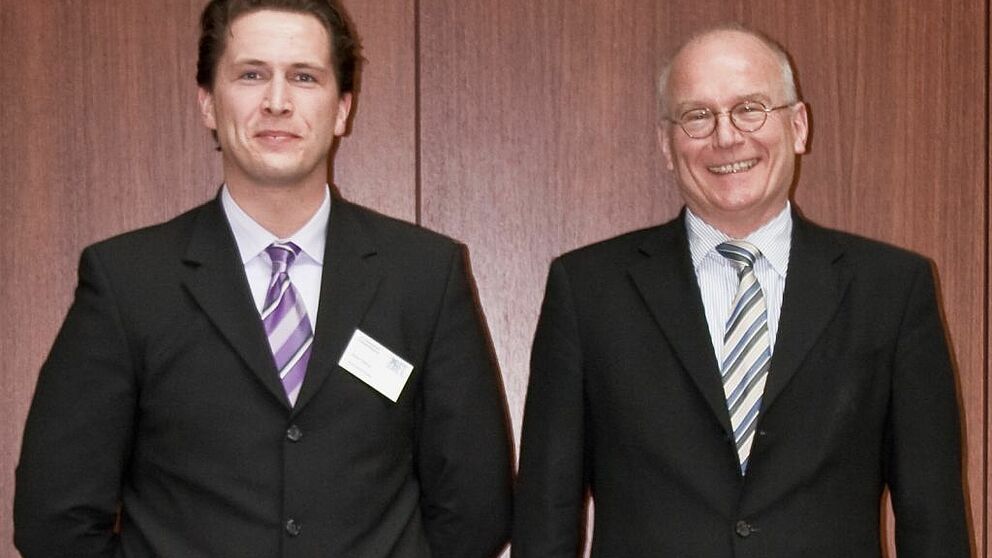 Foto (Universität Paderborn): Prof. Dr.-Ing. habil. Wilhelm Dangelmaier (re.) freut sich mit seinem Doktoranden, Robin Delius (li.), über das Stipendium aus der Industrie.