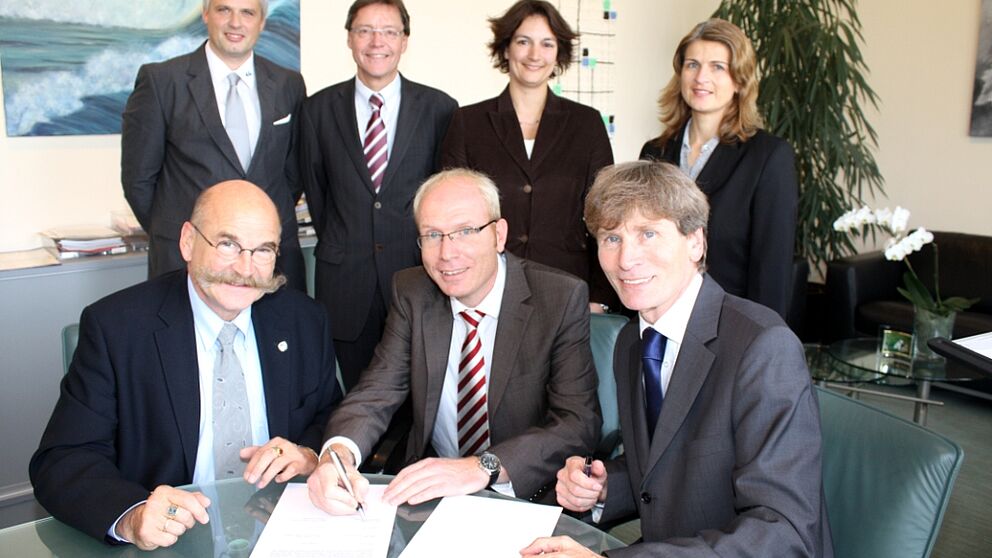 Foto (Frauke Döll): Kanzler Jürgen Plato (links), Präsident Prof. Dr. Nikolaus Risch (rechts)  und Karl-Julius Sänger, Vertriebsleiter OWL der Techniker Krankenkasse, unterzeichnen im Beisein von Hans-Norbert Blome (hinten links), Hochschulberater der