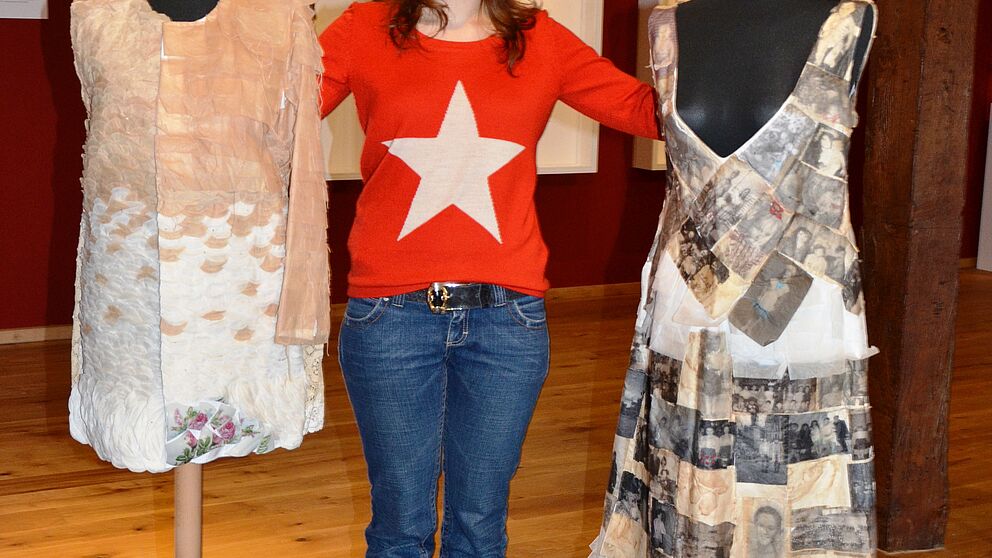 Foto: Helena Arngold mit ihren Werken „Te(e)xtilkleid“ und „Kleid meines Lebens“ (v. l. n. r.)