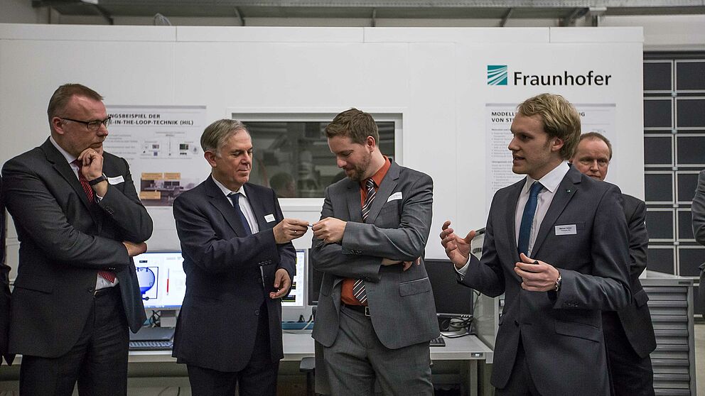 Foto: Eine Station des Institutsrundgangs war der Versuchsstand für einen selbstkorrigierenen Stanzbiegeprozess. V. l. n. r.: Dr. Stefan Schwehr (paragon AG), Dr. Eduard Sailer (Miele & Cie. KG), Prof. Dr. Eric Bodden (Universität Paderborn/Fraunhofer I