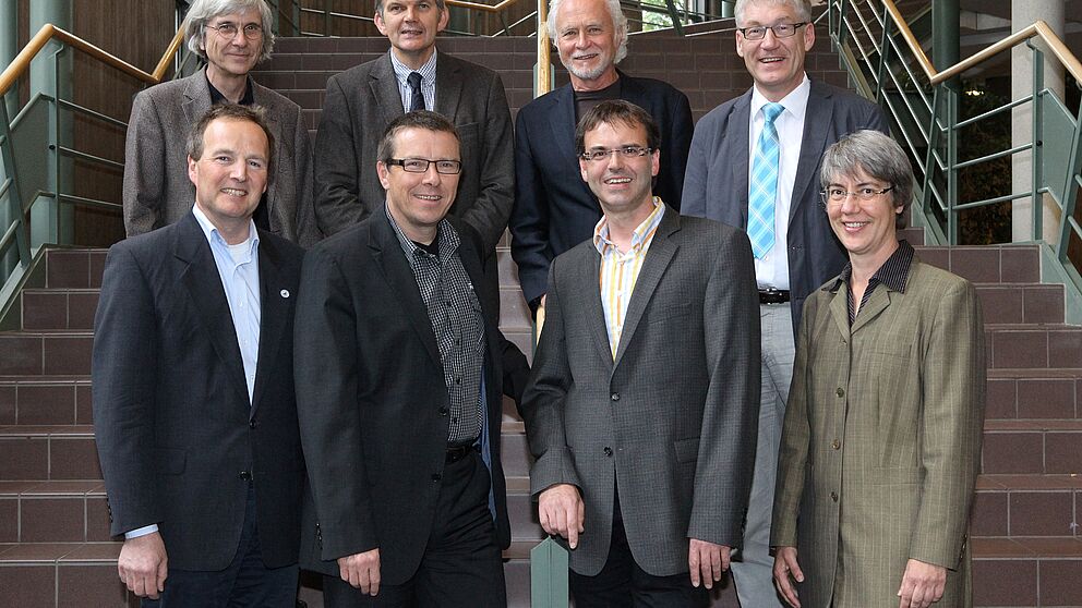 Foto (Uni Paderborn, A. Rutenburges):  (obere Reihe von l.) Dr. Frank Lohse, Prof. Dr. Helmut Heseker, Prof. Dr. Hans-Joachim Warnecke, Prof. Dr. Peter Reinhold  übergeben an (untere Reihe von l.) Dr. Christian Hennig,  Prof. Dr. Hans Peter Brandl-Breden