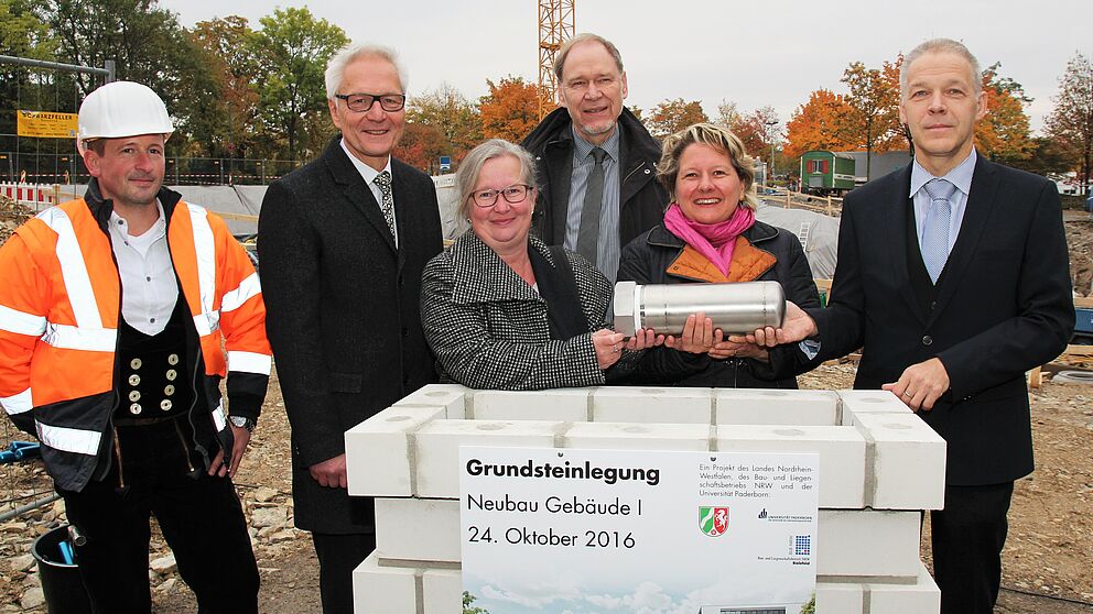 Foto (Universität Paderborn, Vanessa Dreibrodt): (v. l.) Gemeinsam mit Polier Mathias Bust versenkten Martin Pantke, stellv. Bürgermeister Stadt Paderborn, Simone Probst, Vizepräsidentin der Universität Paderborn, Rolf Holler, Niederlassungsleiter des
