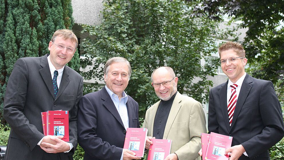 Foto (Universität Paderborn, Martin Decking): Herausgeber Dr. Ingo-G. Wenke (3. v. li) überreicht Dr. Michael Laska (2. v. li.), Geschäftsführer Fakultät für Elektrotechnik, Informatik und Mathematik, 50 Exemplare des neuen Buches „Arbeitsmarkt El