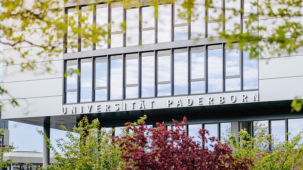 In the background sharp the building Q of Paderborn University, in the foreground blurred trees.
